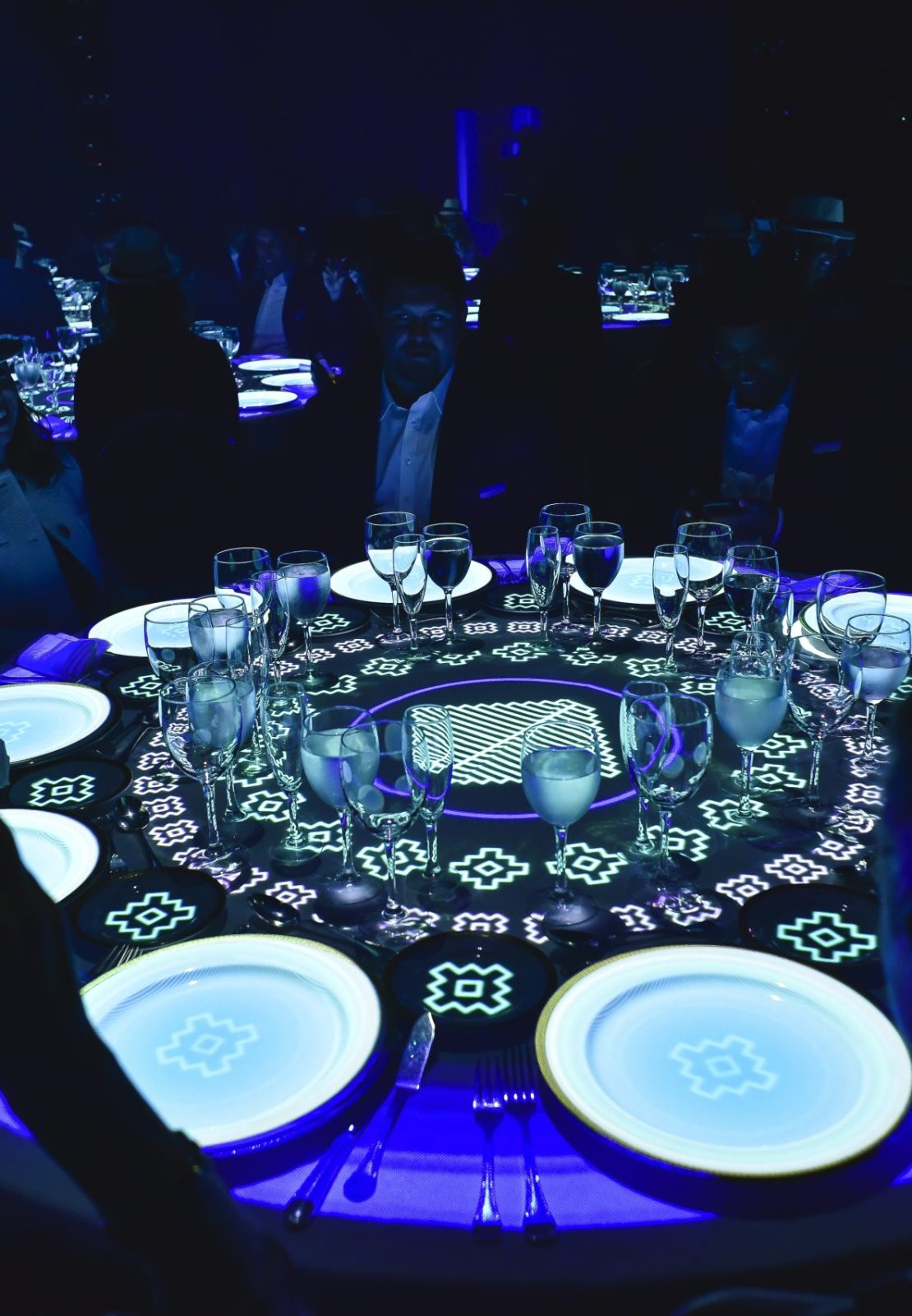 Guests seated around an illuminated interactive dining table during the Conference in Buenos Aires – Immersive 360°, with projected patterns and tableware creating an immersive experience.