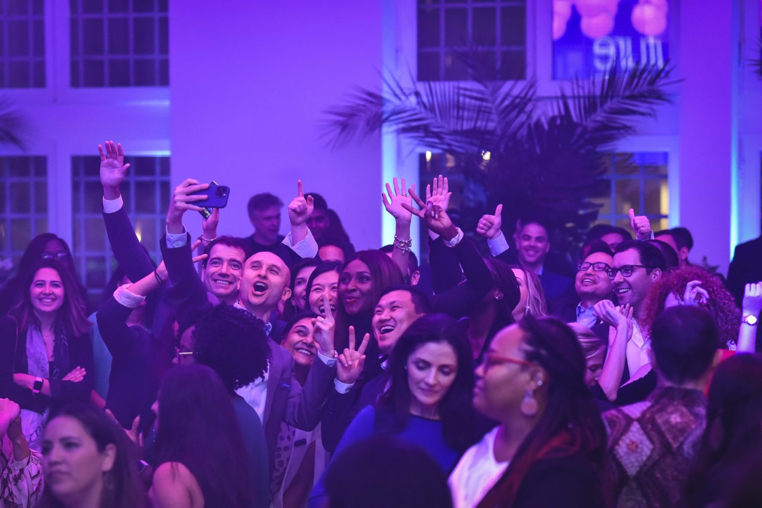 Group of attendees smiling and taking selfies together during the Conference in Buenos Aires – Immersive 360°, in a lively indoor reception with purple lighting.