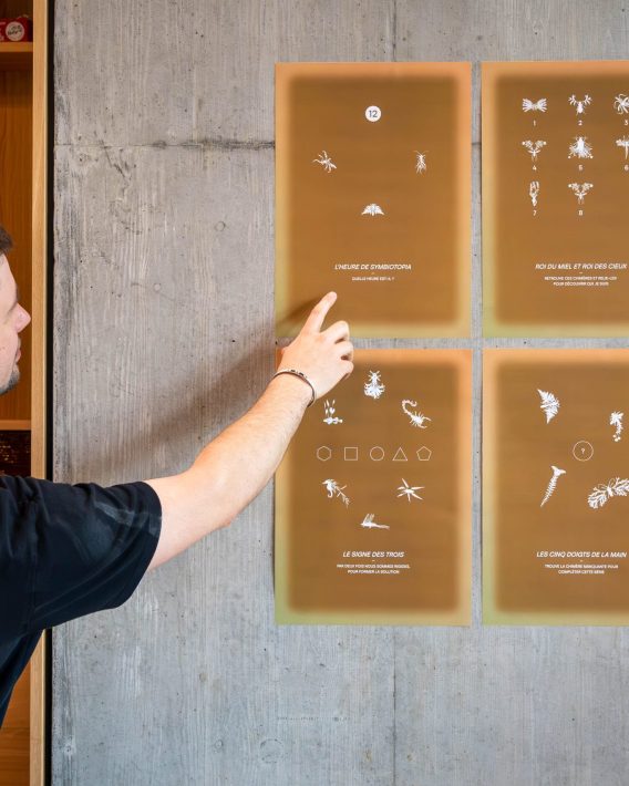 Man interacting with an interactive wall display during the MEA – Opening of MEA at Geneva, pointing at illustrated panels mounted on a concrete wall inside an exhibition space.