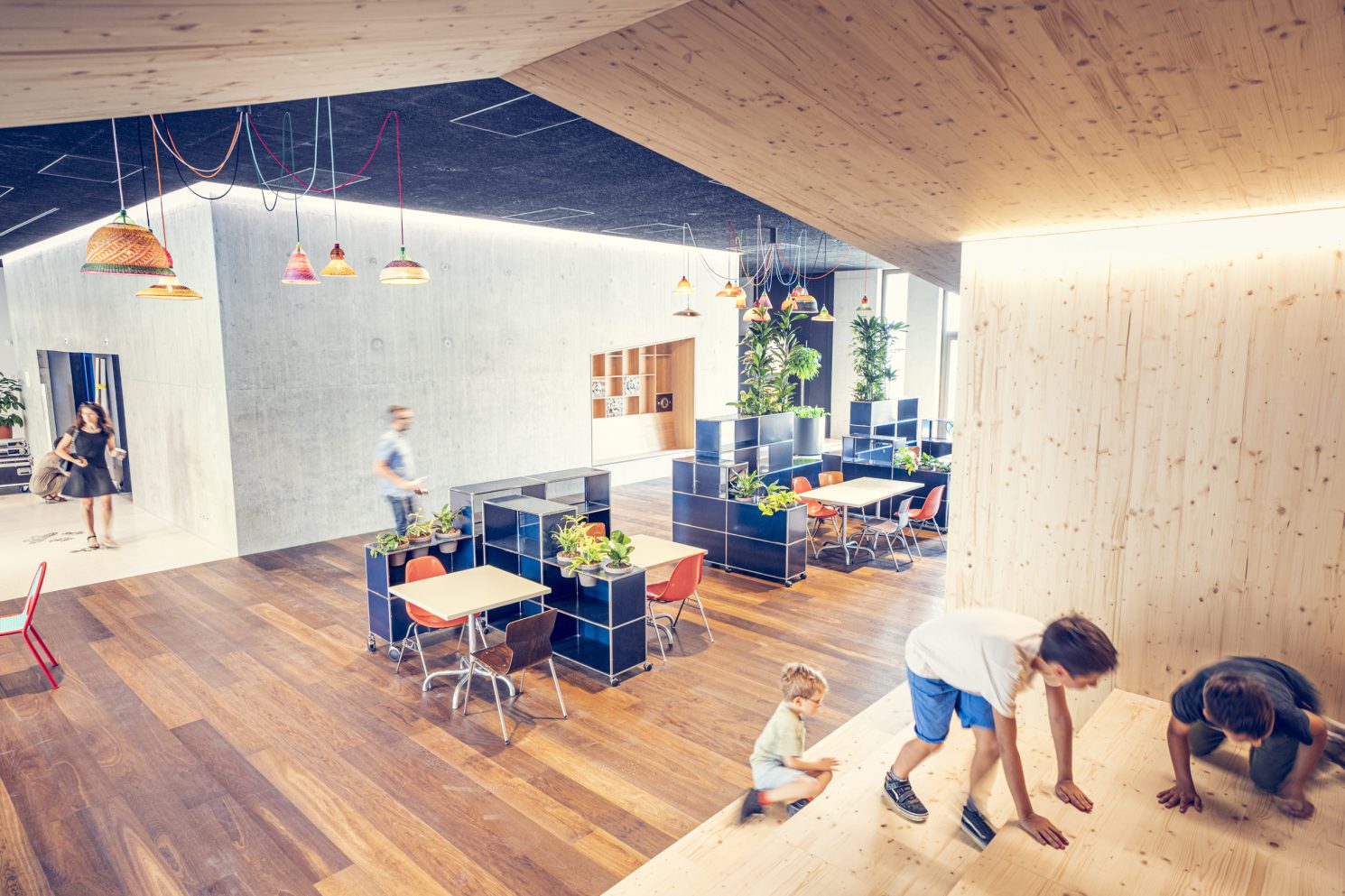 People and children using a modern communal space with wooden interior and seating areas during the MEA – Opening of MEA at Geneva.