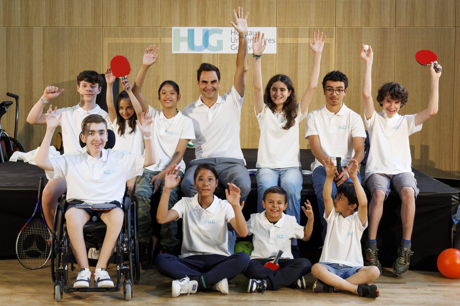 Smiling group of children and adults in HUG polo shirts celebrating together during a sports activity at the MEA – Opening of MEA at Geneva.