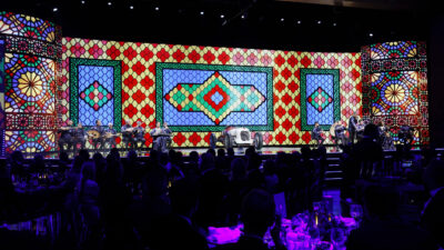 Wide stage view with live musicians, a classic race car, and a large colorful patterned backdrop during the FIA – Motorsport Award Ceremony.