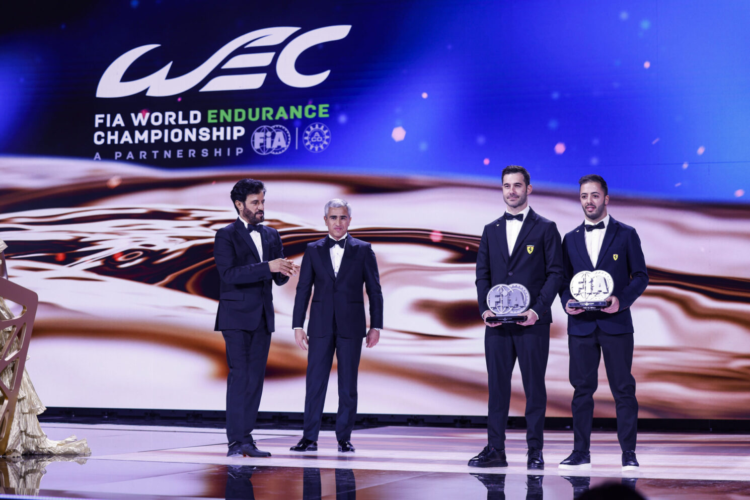 Award presentation on stage during the FIA – Motorsport Award Ceremony, with officials and winners holding trophies in front of a FIA World Endurance Championship backdrop.