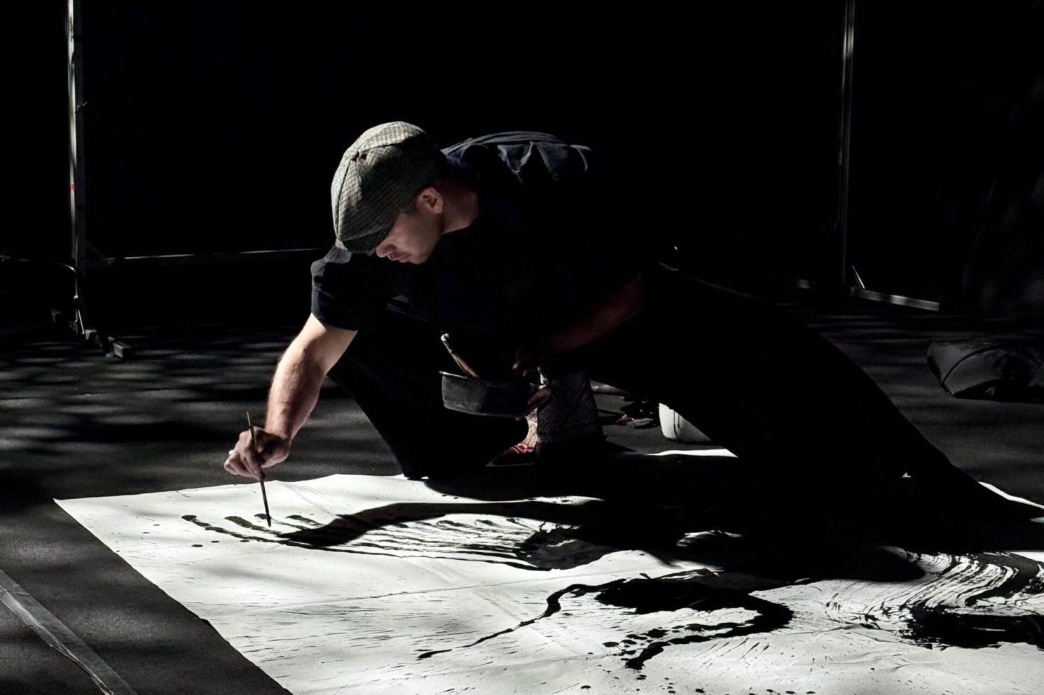 Artist creating expressive black ink brushstrokes on a large canvas during the Mazda – Cinematic reveal of the Mazda 6E.